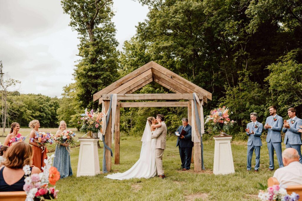 bride and groom kissing under wooden pergola