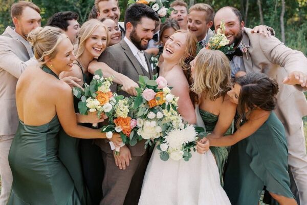 wedding party hugging bride and groom