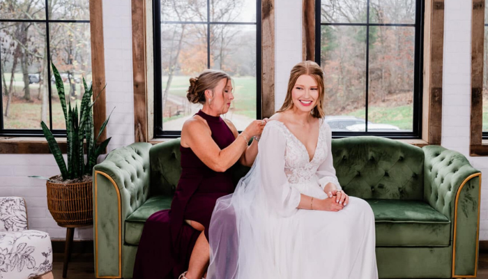 bride and mother sitting on velvet couch in bridal suite